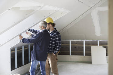 Architekt und Arbeiter messen Fenster auf einer Baustelle aus - MJFKF00206