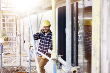 Happy worker on the phone a construction site - MJFKF00258