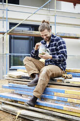 Happy worker having lunch break on a construction site - MJFKF00260