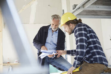 Architekt und Arbeiter besprechen einen Bauplan auf einer Baustelle - MJFKF00275