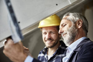 Architekt und Arbeiter messen Fenster auf einer Baustelle aus - MJFKF00281