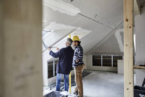 Architekt und Arbeiter messen Fenster auf einer Baustelle aus - MJFKF00283