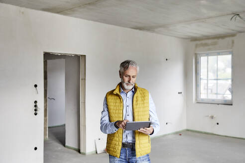 Älterer Mann benutzt Tablet auf einer Baustelle - MJFKF00286