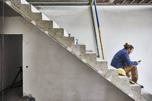 Construction worker using smartphone at construction site - MJFKF00289