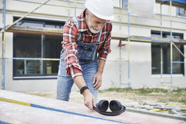 Bauarbeiter mit Ohrenschützer bei der Arbeit auf der Baustelle - MJFKF00305