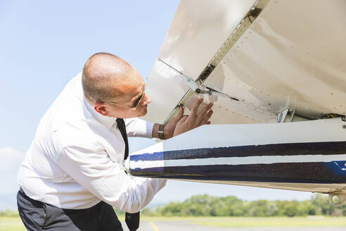 Pilot bei der Vorflugkontrolle seines Sportflugzeugs - WPEF02926