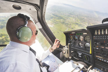 Pilot fliegt im Sportflugzeug, VFR-Karte auf dem Schoß - WPEF02937