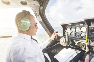 Pilot flying in sports plane, using control wheel - WPEF02938