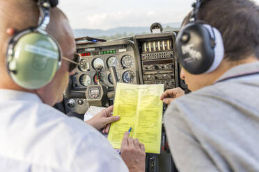 Flugzeug und Kopilot sitzen im Sportflugzeug und gehen die Checkliste durch - WPEF02949