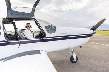 Pilot mit Headset, sitzend im Sportflugzeug - WPEF02952