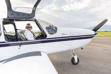 Pilot with headset, sitting in sports plane - WPEF02952