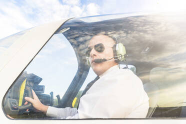 Pilot with headset, sitting in sports plane - WPEF02953
