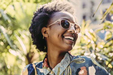 Portrait of happy young woman wearing sunglasses in garden - MFF05811