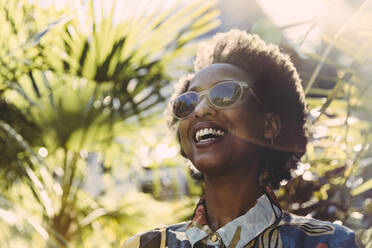 Portrait of happy young woman wearing sunglasses in garden - MFF05812