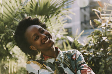 Porträt einer glücklichen jungen Frau, die sich im Garten entspannt - MFF05814