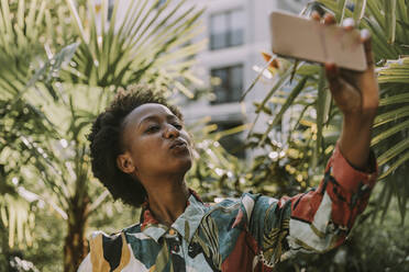 Portrait of young woman taking selfie with smartphone in garden - MFF05815