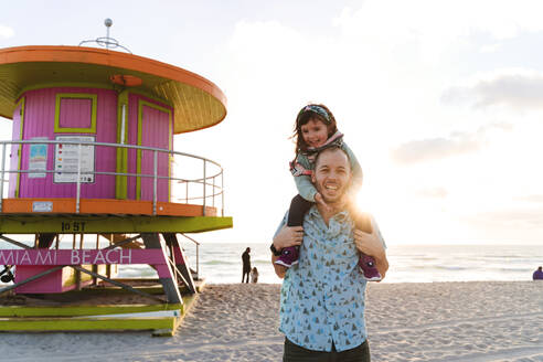 Glücklicher Vater trägt Tochter auf den Schultern am Strand von Miami, Florida, USA - GEMF03790