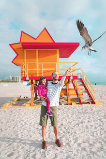 Vater mit Tochter beim Füttern einer Möwe am Strand von Miami, Florida, USA - GEMF03798