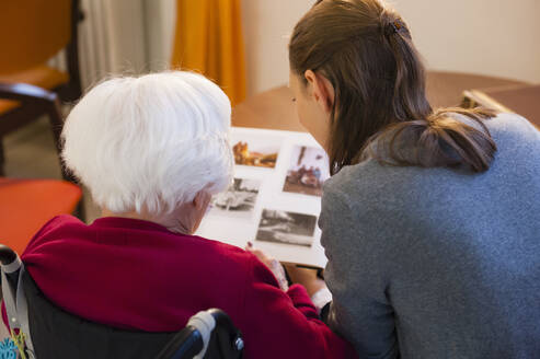 Großmutter mit Enkelin beim Betrachten eines Fotoalbums zu Hause - DIGF12486
