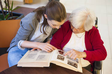 Großmutter mit Enkelin beim Betrachten eines Fotoalbums zu Hause - DIGF12487