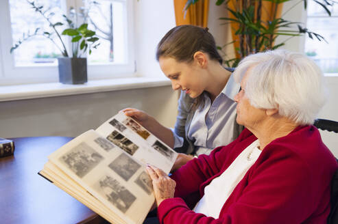 Großmutter und Enkelin schauen sich zu Hause ein Fotoalbum an - DIGF12489