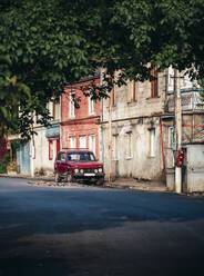 Georgien, Imereti, Kutaisi, Auto an alten Gebäuden geparkt - WVF01668