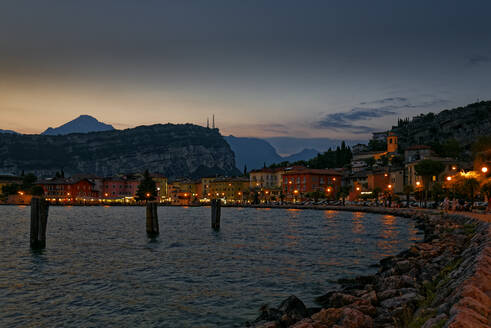 Italien, Trentino, Torbole, Gardasee, Promenade und Stadt in der Abenddämmerung beleuchtet - UMF00924