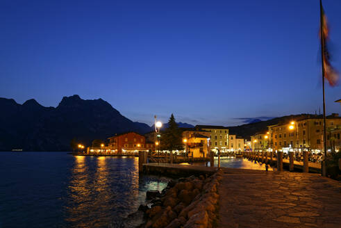 Italien, Trentino, Torbole, Gardasee, Promenade und Stadt in der Abenddämmerung beleuchtet - UMF00925