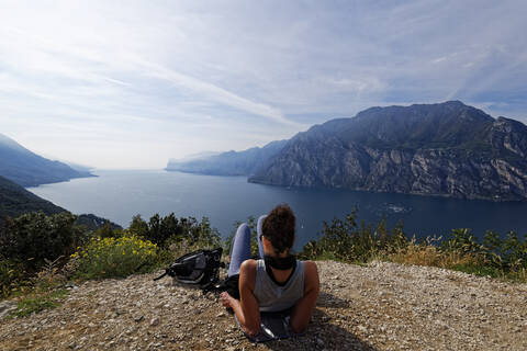 Italy, Trentino, Torbole, Rear view of woman looking at Lake Garda surrounded with mountains  stock photo