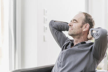 Portrait of mature man with eyes closed relaxing with hands behinds his head - UUF20399