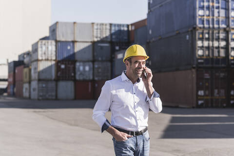 Porträt eines Geschäftsmannes am Telefon vor einem Frachtcontainer, lizenzfreies Stockfoto