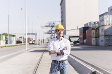 Porträt eines Geschäftsmannes mit Schutzhelm auf einem Industriegelände - UUF20419