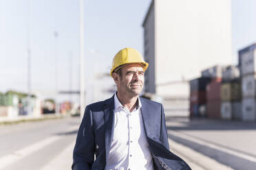 Porträt eines Geschäftsmannes mit Schutzhelm auf einem Industriegelände - UUF20429