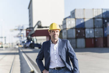 Porträt eines Geschäftsmannes mit Schutzhelm auf einem Industriegelände - UUF20433
