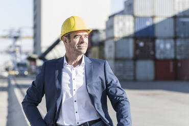 Porträt eines Geschäftsmannes mit Schutzhelm auf einem Industriegelände - UUF20434