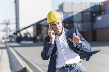 Porträt eines Geschäftsmannes, der in einem Industriegebiet telefoniert - UUF20435
