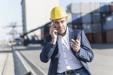 Porträt eines Geschäftsmannes, der in einem Industriegebiet telefoniert - UUF20436