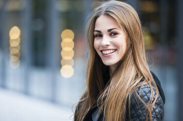 Schöne junge Frau mit langen braunen Haaren lächelnd im Freien - DIGF12529