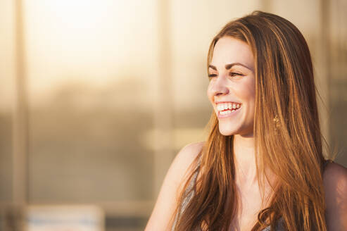 Schöne junge Frau mit langen braunen Haaren lächelnd am sonnigen Tag - DIGF12540
