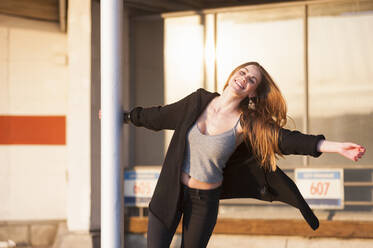 Beautiful young woman swinging around metallic pole in city - DIGF12541