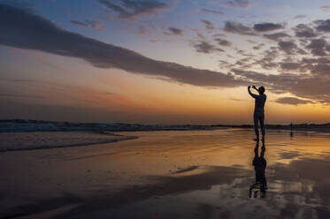 Mann, der ein Smartphone-Foto bei Sonnenuntergang am Meer macht, Gran Canaria, Spanien - DIGF12550