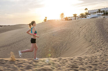 Woman running in the dunes at sunrise, Gran Canaria, Spain - DIGF12576