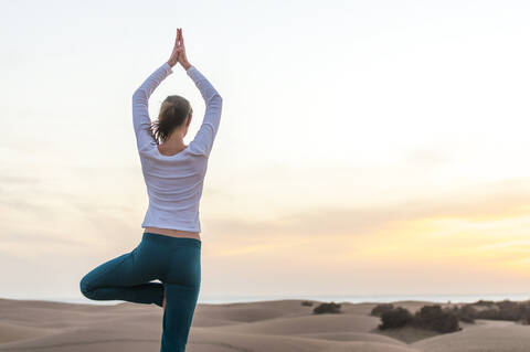 Frau übt Yoga bei Sonnenuntergang in den Dünen, Gran Canaria, Spanien, lizenzfreies Stockfoto