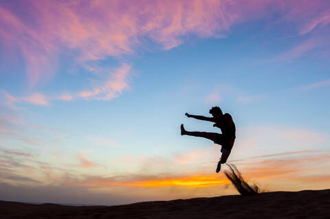 Silhouette of man jumping at sunset in the dunes, Gran Canaria, Spain stock photo