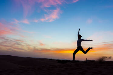 Silhouette of woman jumping at sunset in the dunes, Gran Canaria, Spain - DIGF12585