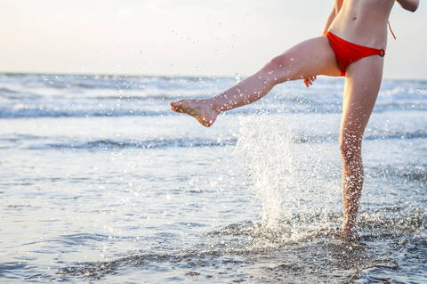 Legs of a woman splashing with water in the sea stock photo