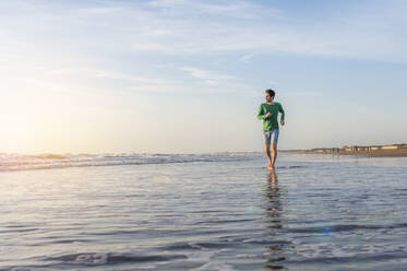 Man running in the sea at sunrise, Gran Canaria, Spain - DIGF12593