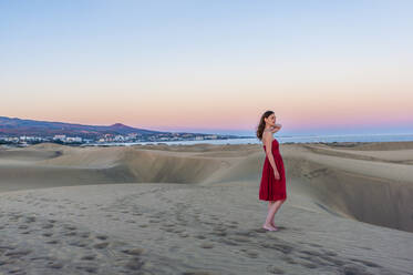 Frau in rotem Kleid bei Sonnenuntergang in den Dünen, Gran Canaria, Spanien - DIGF12608