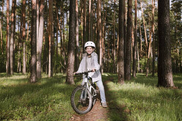 Glücklicher Junge mit Fahrrad im Wald - EYAF01076