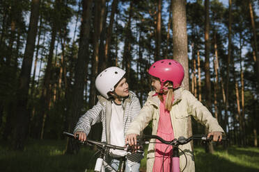 Mädchen und Junge unterhalten sich beim Fahrradfahren im Wald - EYAF01084
